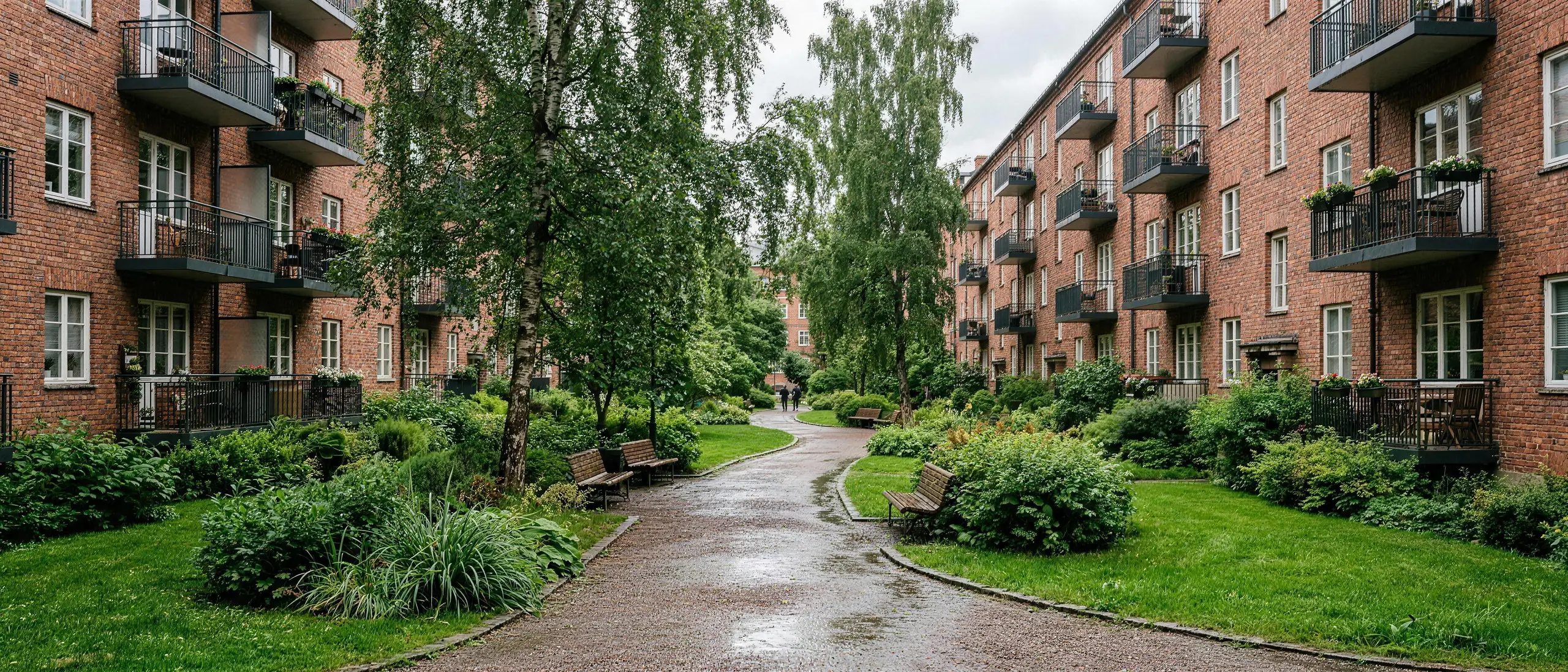 Gårdsrom mellom boligblokker i Oslo med benker og trær, mennesker på avstand, dagslys.