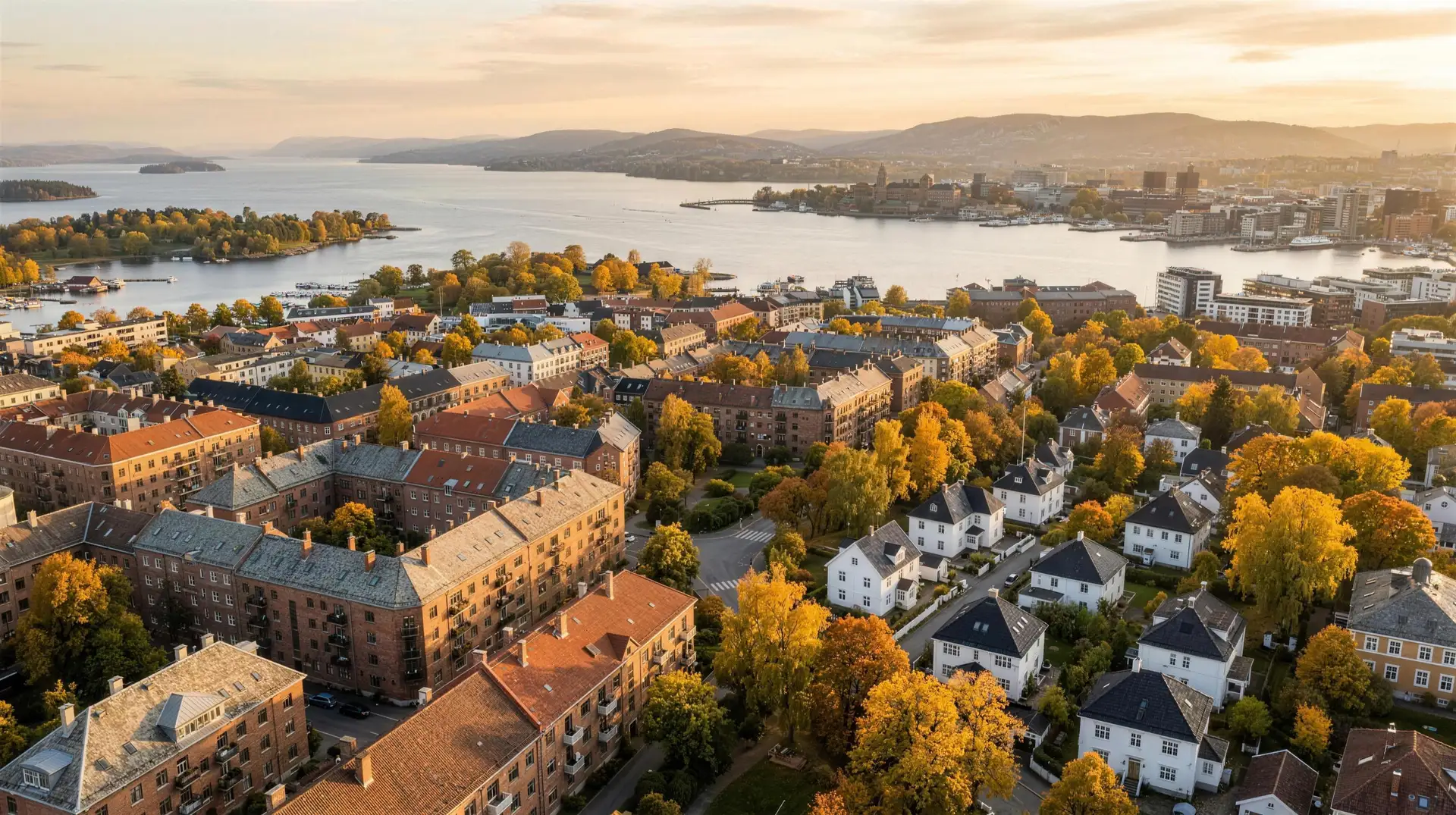 Oslo sett fra lufta i gyllen kveldssol, boligblokker og småhus mot fjorden. Illustrasjon laget med kunstig intelligens.