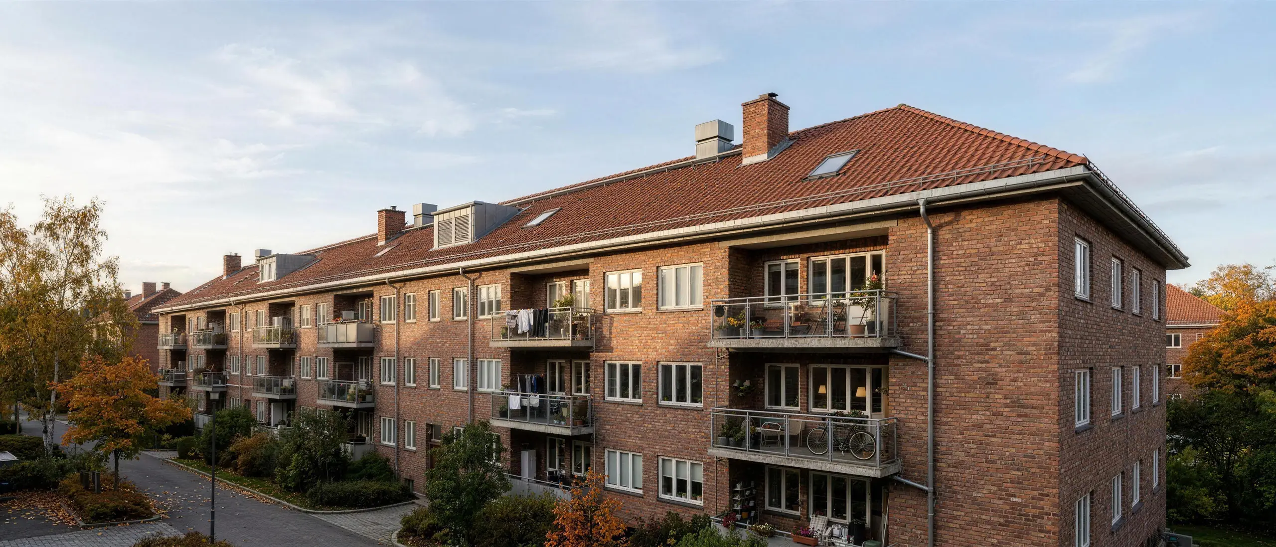 Detalj av tak og takrenne på boligblokk under befaring, overskyet dagslys, ingen mennesker.
